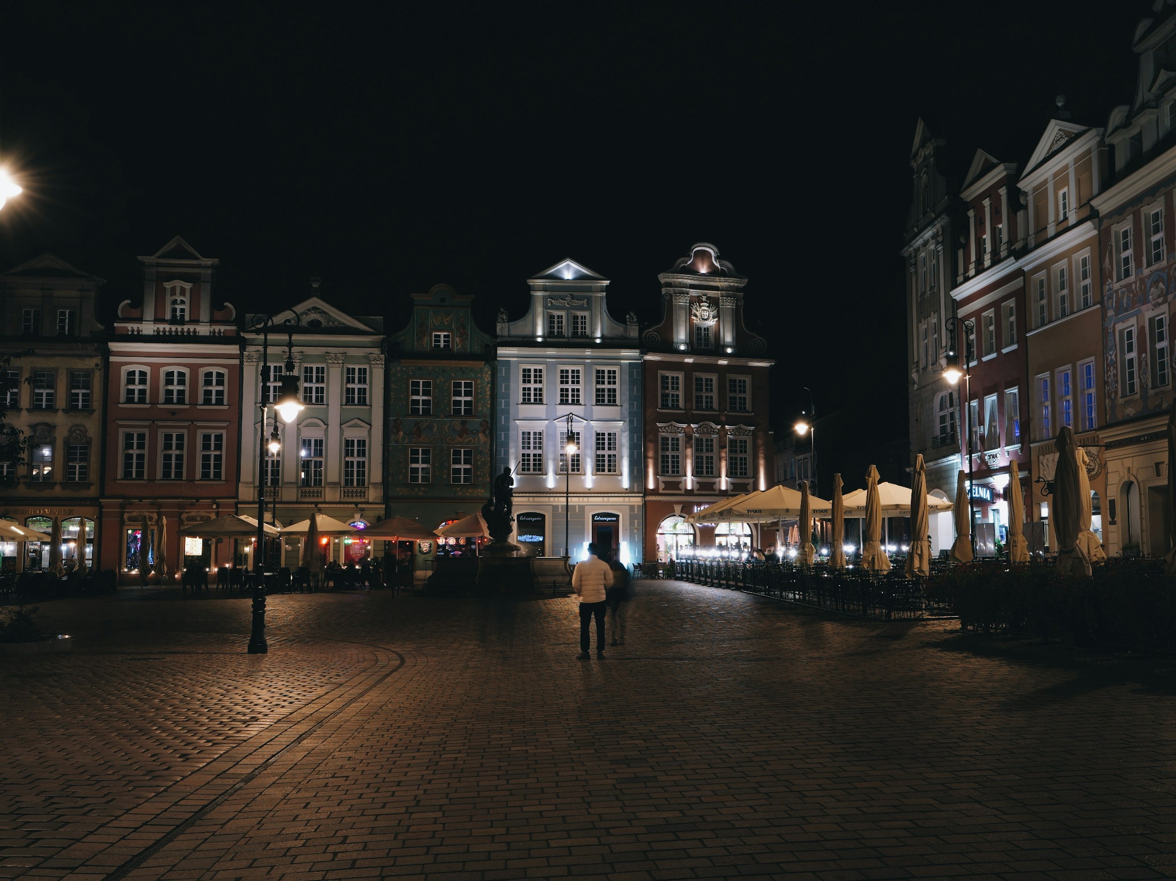 Stary Rynek w Poznaniu nocą, samotny przechodzień na pustym placu